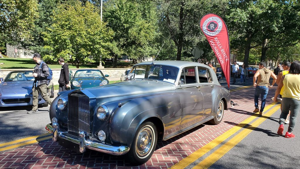 a teardrop flag banner next to a Rolls Royce