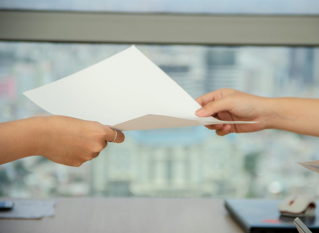 Two people passing paper