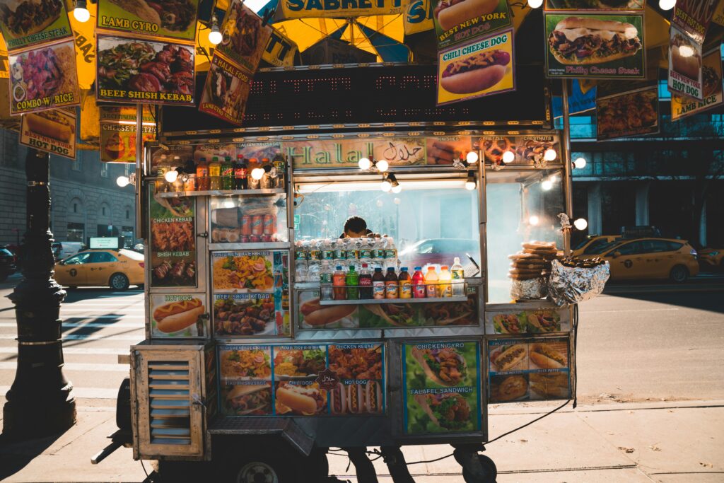Person behind food cart with food stand signs