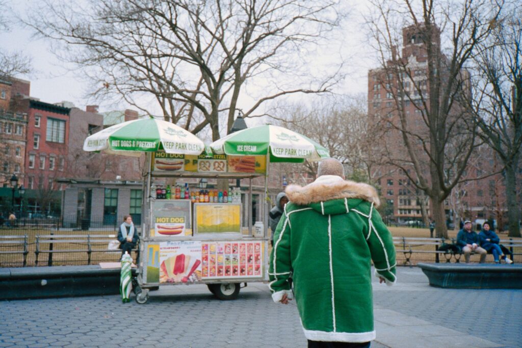 Person standing in front of hot dog vendor cart