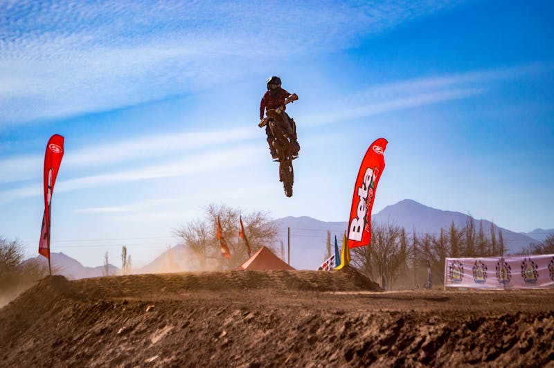 Motorcycle flying through air with flags in background